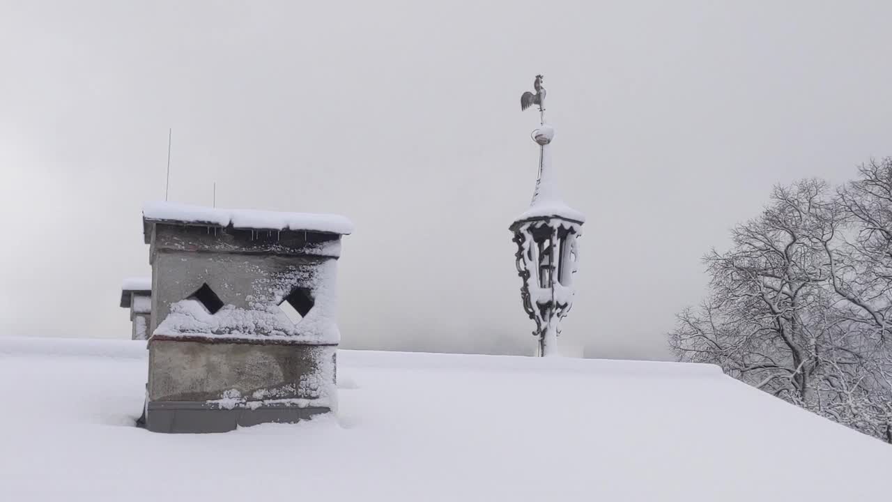 雪覆盖的屋顶在冬天与烟囱和风公鸡视频素材