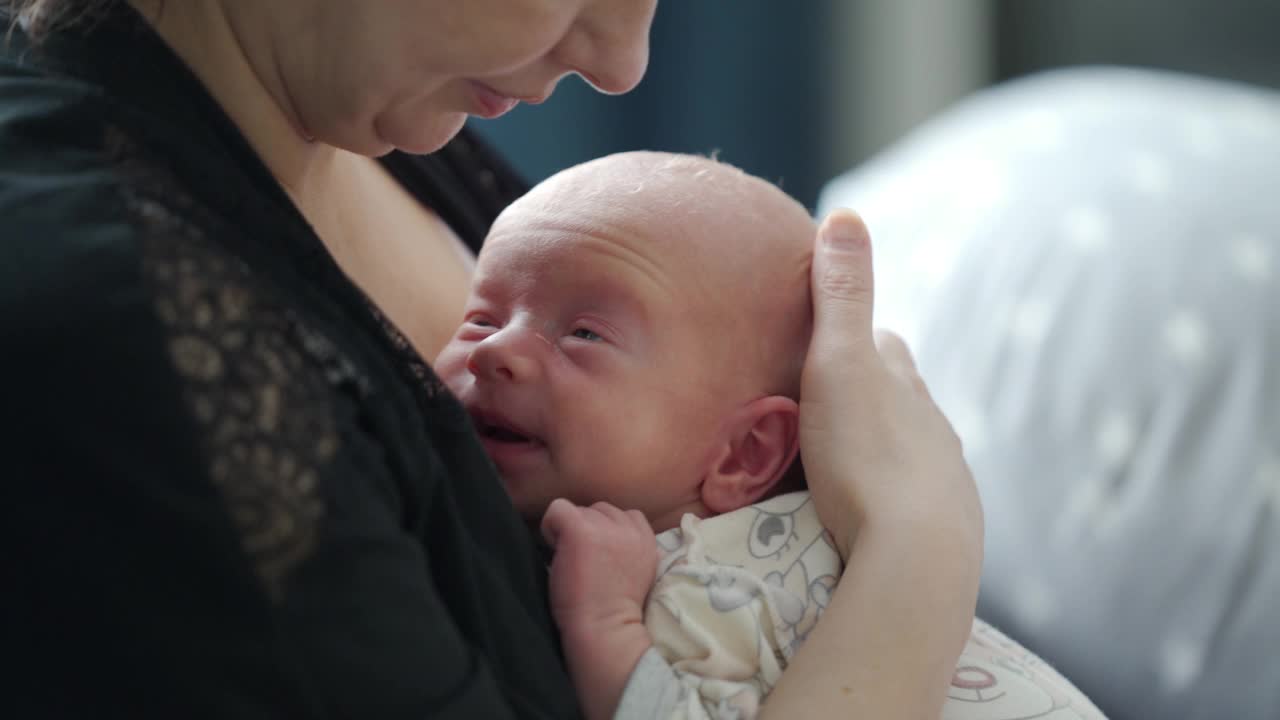 母亲抱着刚出生的婴儿在家里母乳喂养视频素材