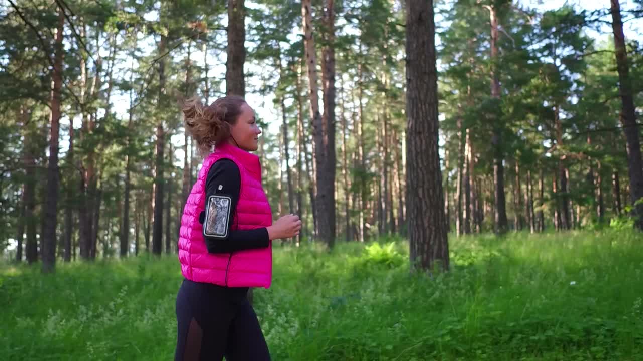 美丽的女孩穿着运动服，在春天的山林里奔跑视频素材