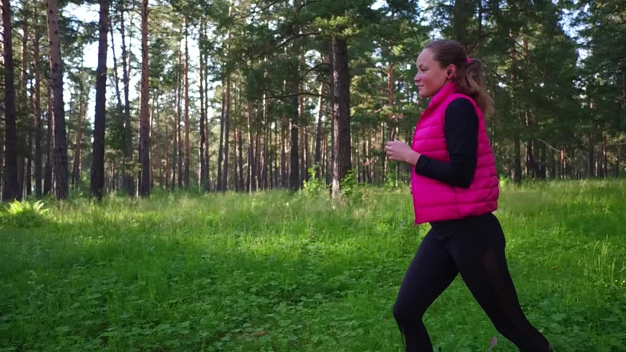 美丽的女孩穿着运动服，在春天的山林里奔跑视频素材