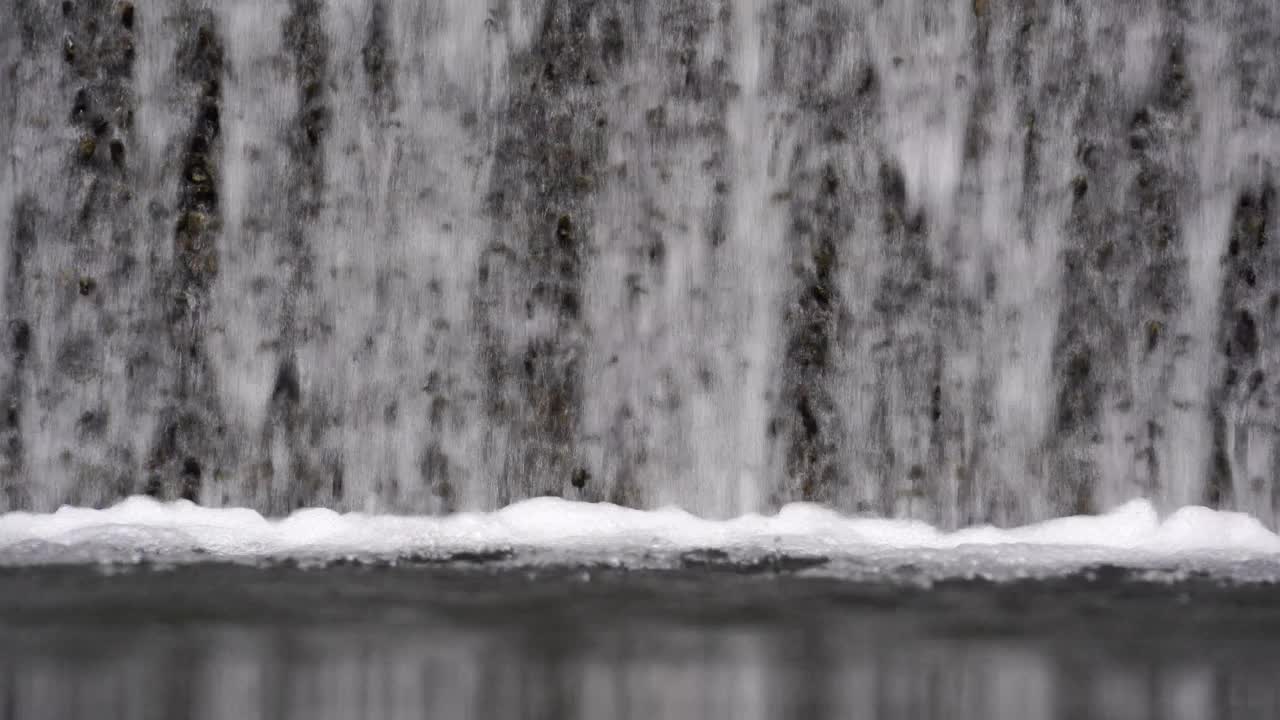 近距离看，水从石墙倾泻到泳池边视频素材