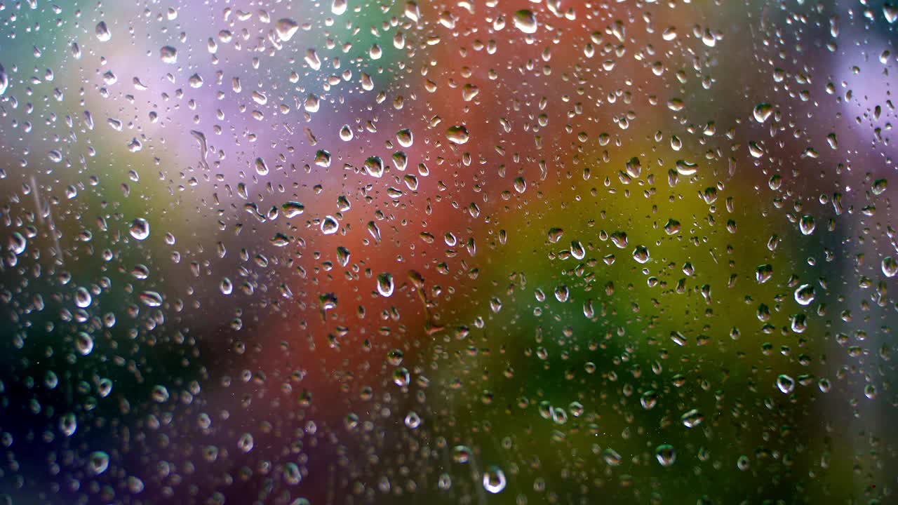 玻璃与雨滴。水滴在窗口上模糊的彩色背景。外面的雨。水滴的背景。特写镜头。视频素材