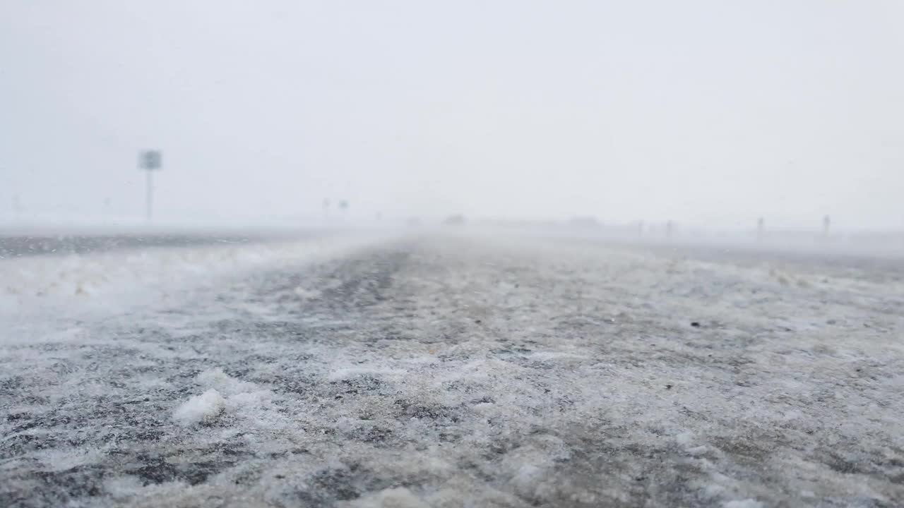 路上有暴风雪，特写。大雪扫过道路。视频下载