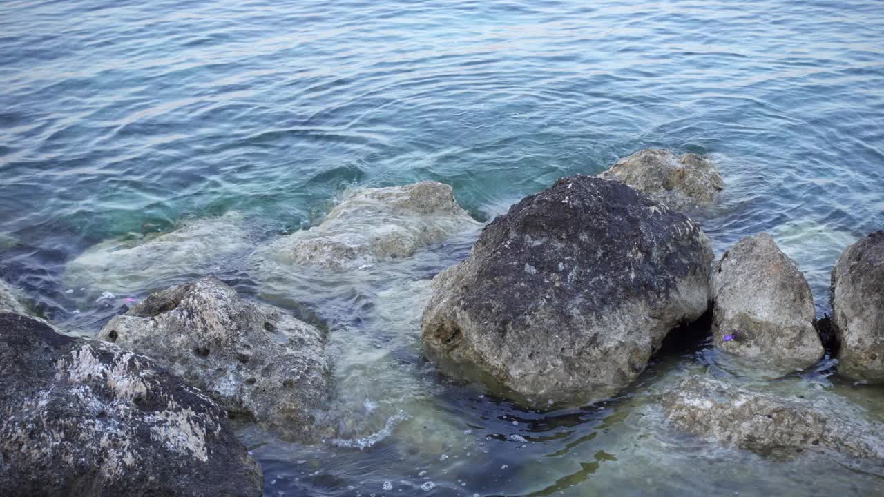 日落时蓝色大海的景色。近距离拍摄海水拍打着地中海的岩石视频素材