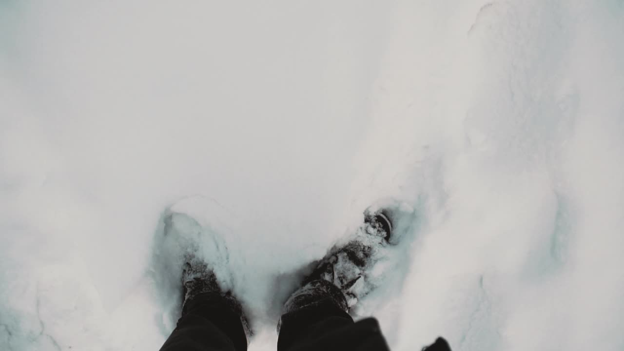 在新雪上行走的男人的腿俯视图视频素材