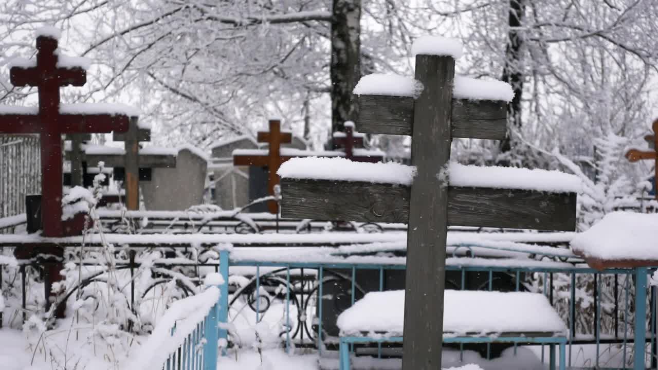 在冬天以慢动作拍摄的墓地上被雪覆盖的十字架的特写镜头视频素材