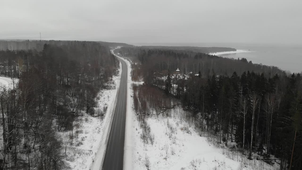 海湾湖附近的柏油路。冬天和雪。森林。灰色沉闷的天气。空中视频素材