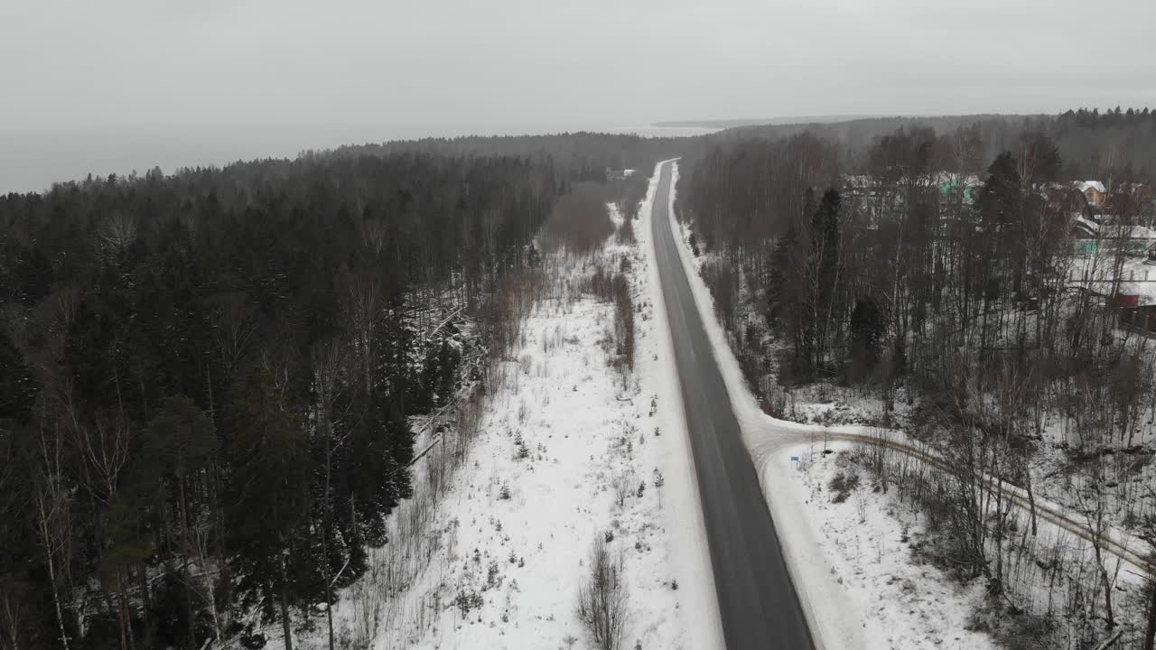 海湾湖附近的柏油路。冬天和雪。森林。灰色沉闷的天气。空中视频素材