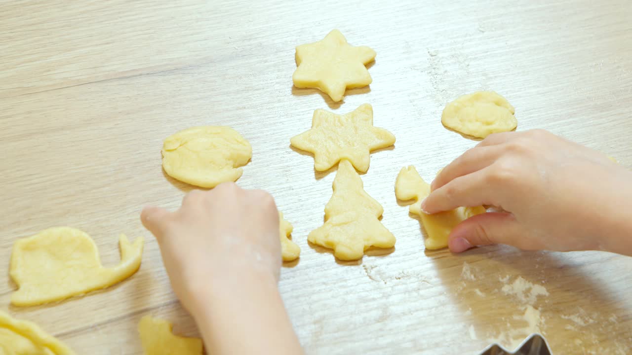 一个孩子的手准备卷曲的饼干从面团在桌子上的特写。视频素材