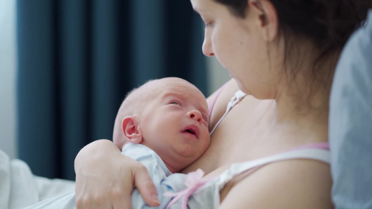 妈妈抱着刚出生的婴儿，妈妈和她3周大的小男孩躺在床上视频素材