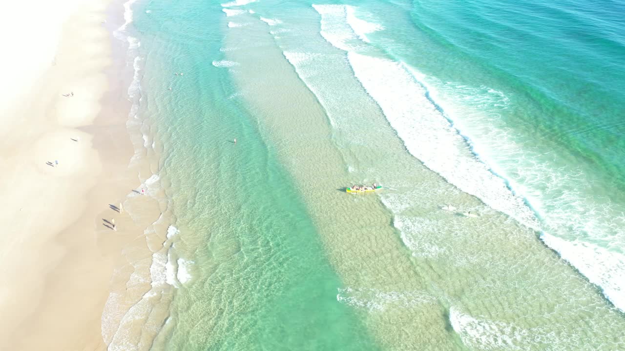 人们和一艘冲浪船在黄金海岸清澈的海水岸边的视频视频下载