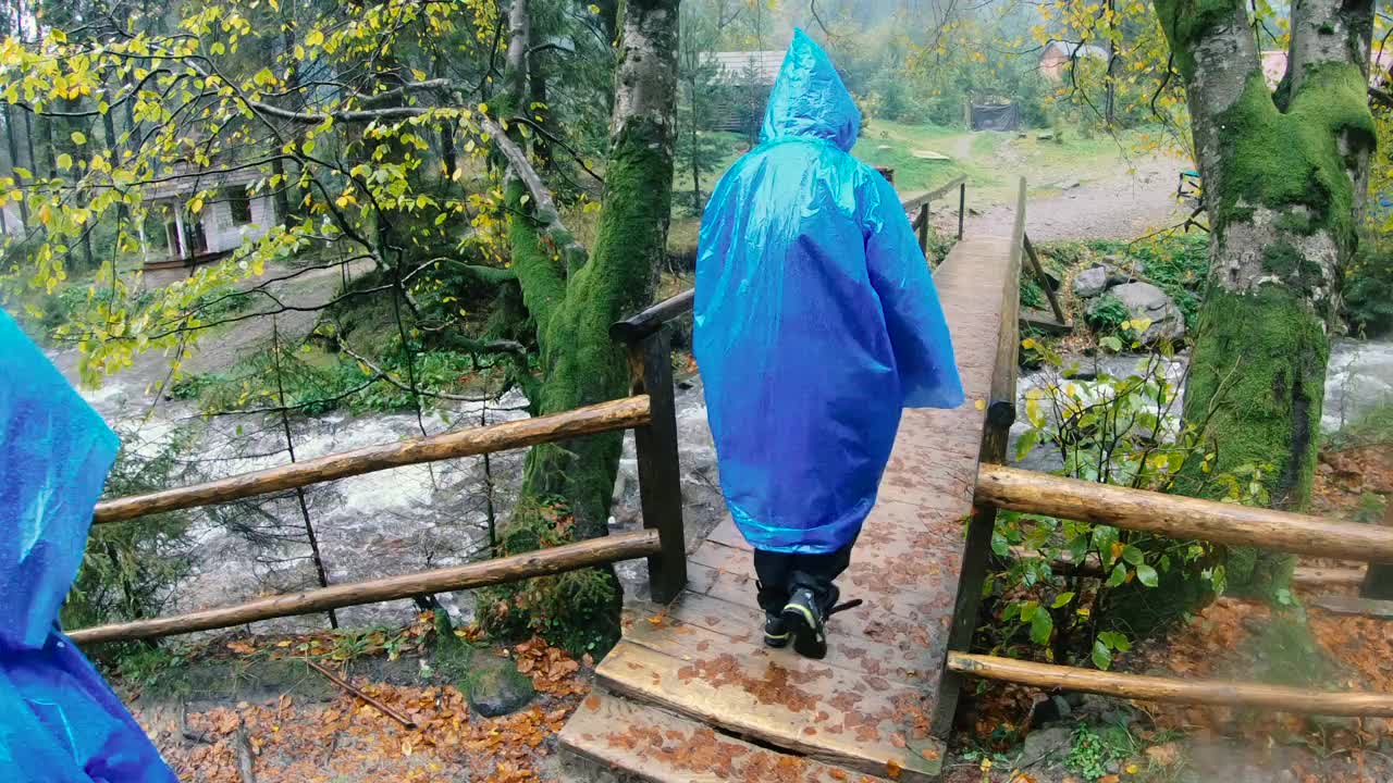 雨衣。两个穿着雨衣的妇女走过一座木桥。视频素材