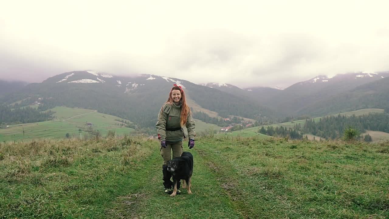 旅行。这个女孩带着狗徒步在山里旅行。视频素材