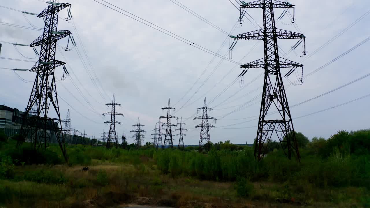 电网络。高压塔负责配电。高压线在现场的植物背景。视图从下面。视频素材