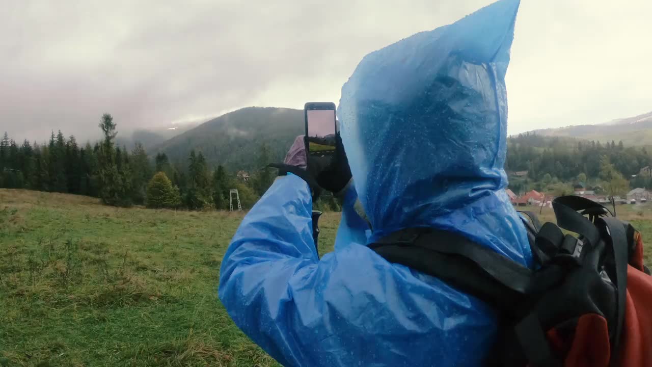 雨衣。一个穿着雨衣的女人正在用她的手机拍照。视频素材