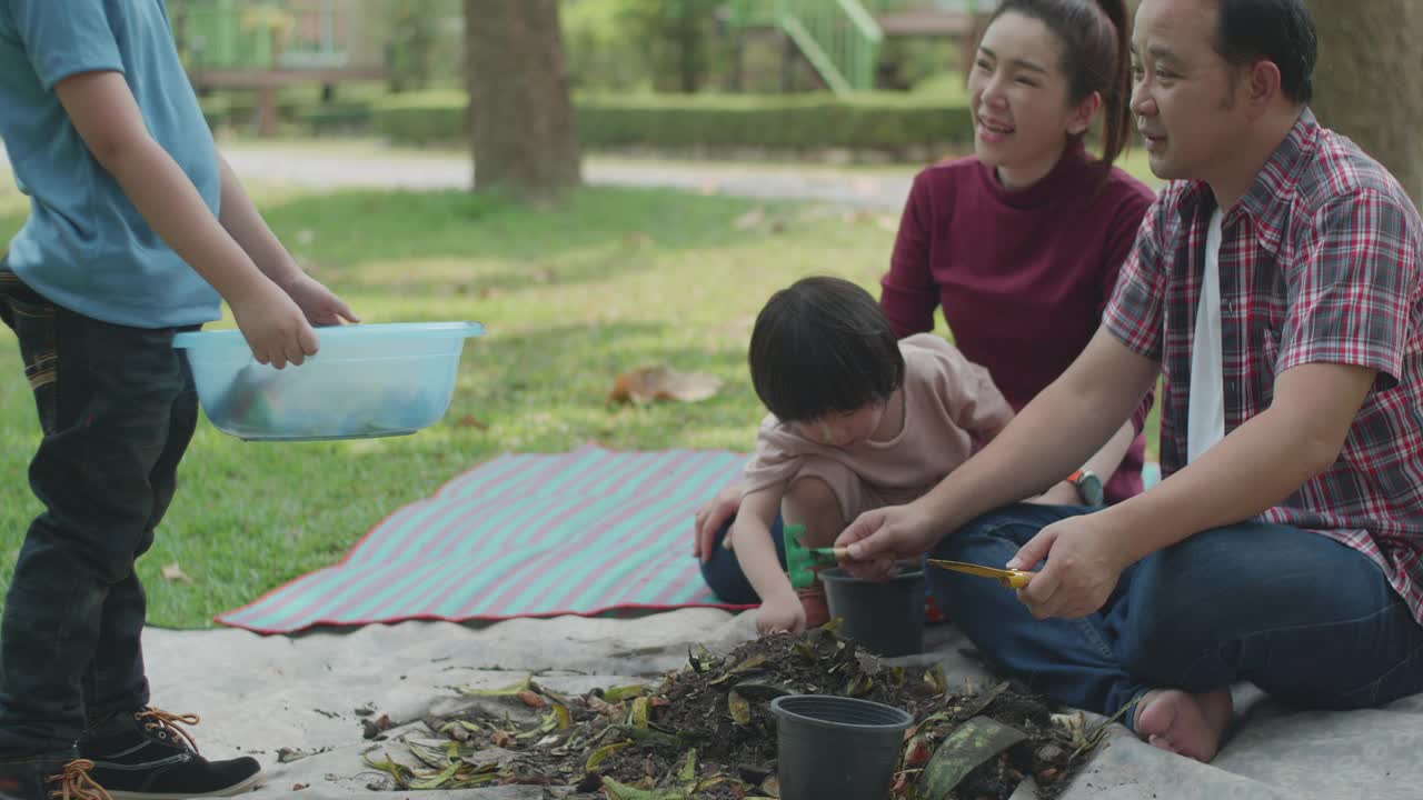 一家人教他们的两个儿子如何用厨房和花园的废弃物制作有机肥料视频素材