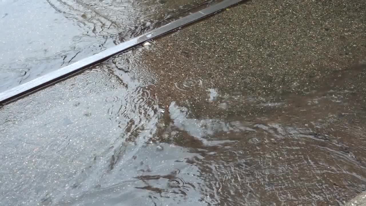 秋雨在城市里，人们的双腿在沥青路面上走过水坑视频下载