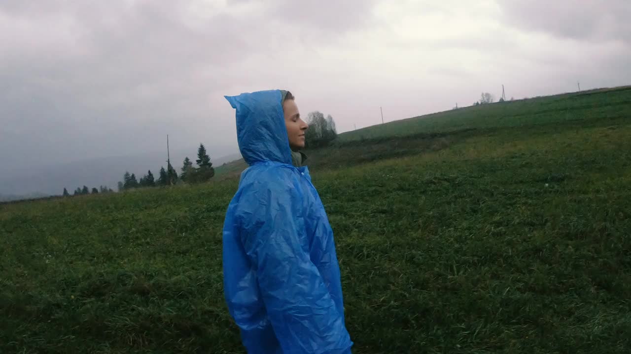 雨衣。一个女人穿着蓝色的雨衣在雨中行走。间隔拍摄。视频素材