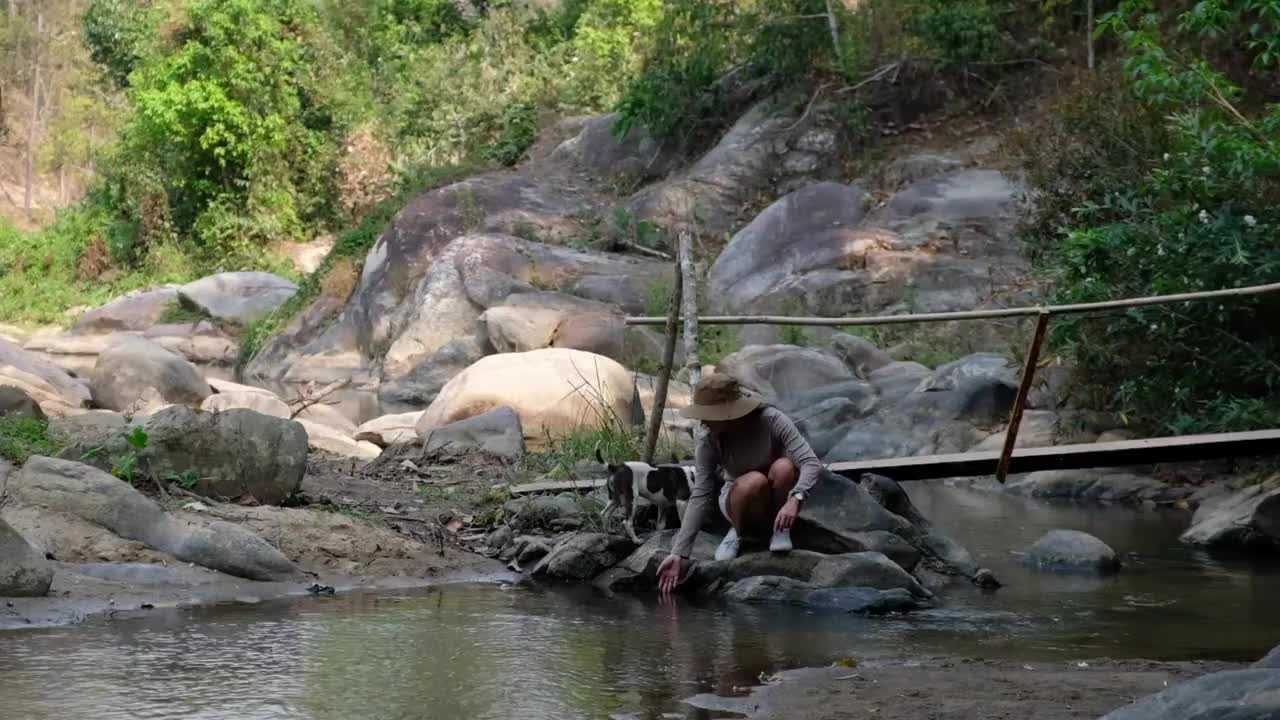 一个女性旅行者在森林里的河里玩和溅水的慢动作视频素材