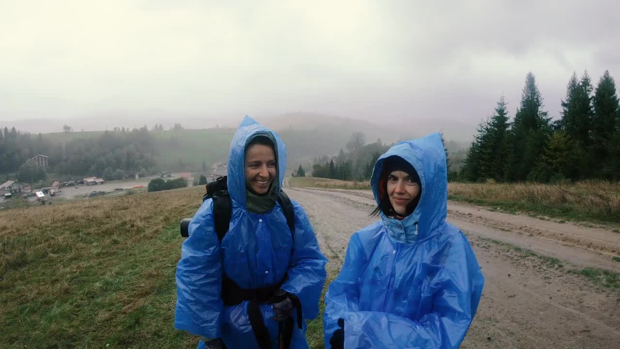 雨衣。两个穿着雨衣的女人挥舞着双手。视频素材