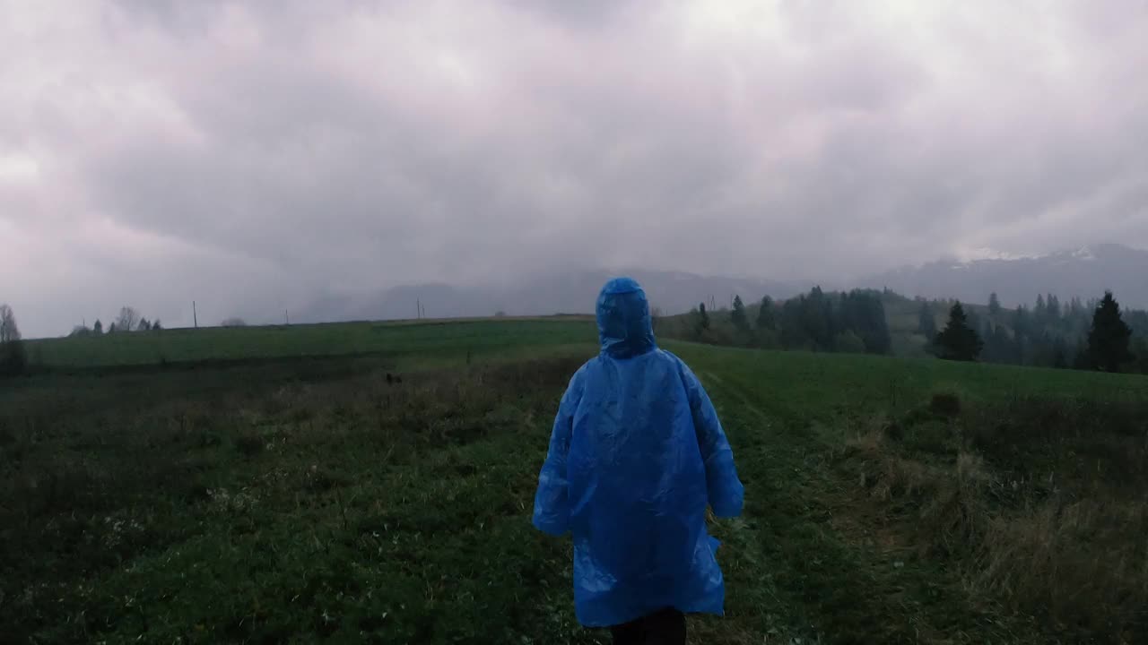 雨衣。一个女人穿着蓝色的雨衣在雨中行走。间隔拍摄。视频素材