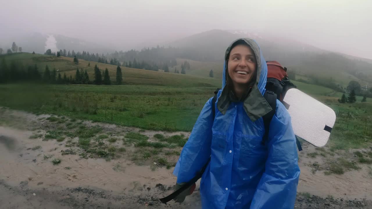 雨衣。一个女人穿着防水雨衣背着背包在雨中行走。视频素材