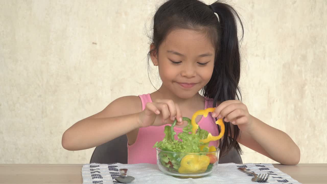 快乐的亚洲小女孩吃蔬菜沙拉视频素材