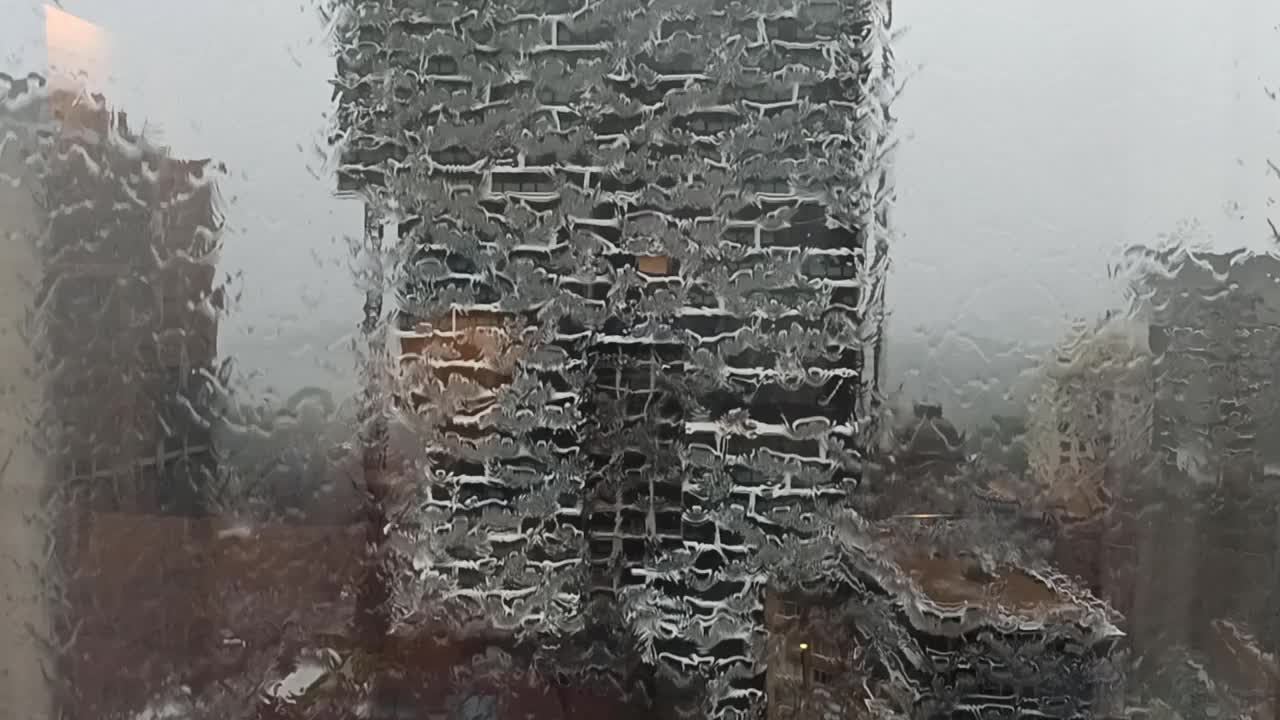 糟糕的雨季。城市里的雨天。雨飞溅着打在窗户上，大雨倾盆。坏天气乌云密布。灰色的云层背景。秋天的雨云。夏季降水。水滴下窗视频素材