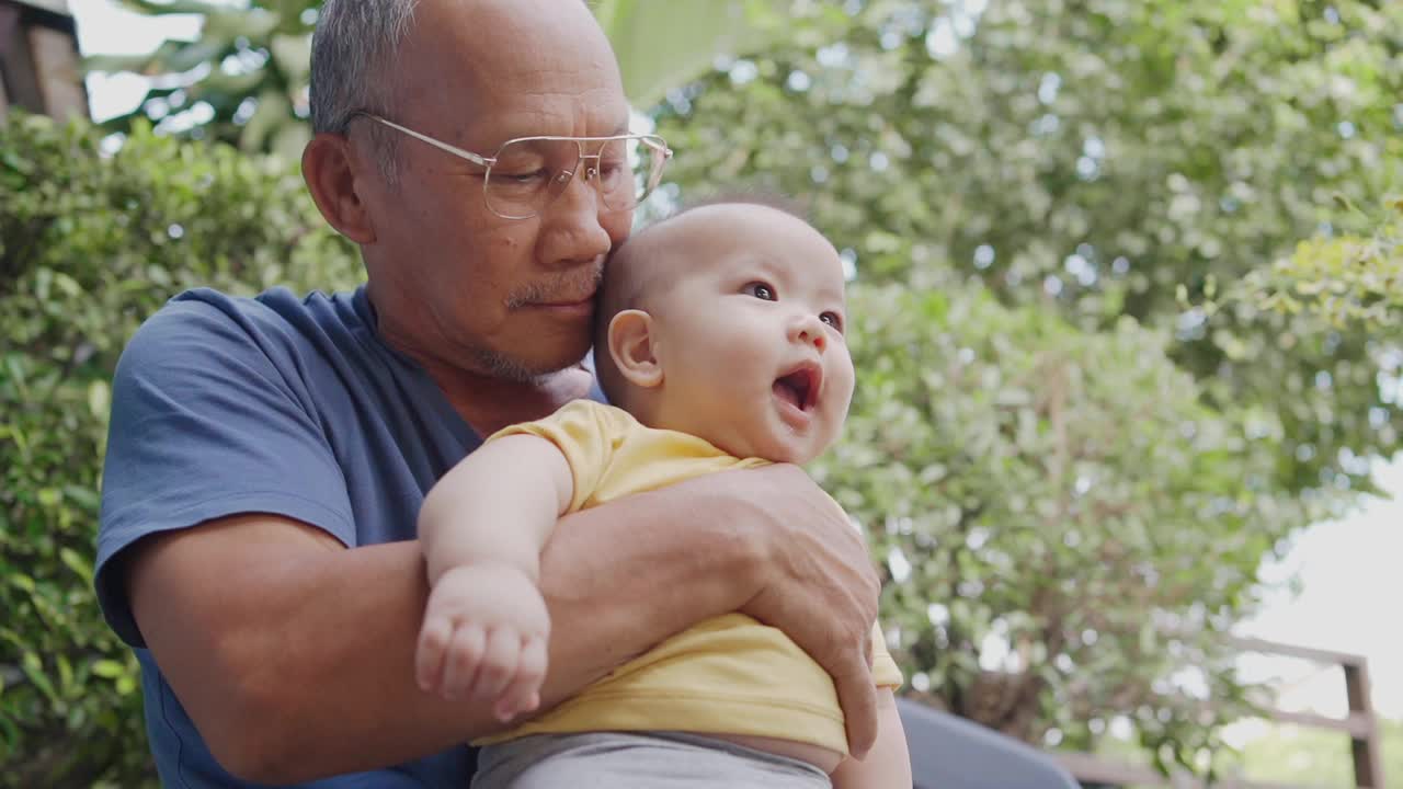 快乐的亚洲爷爷在家里玩和抱着他的小孙子。家庭的乐趣。视频素材