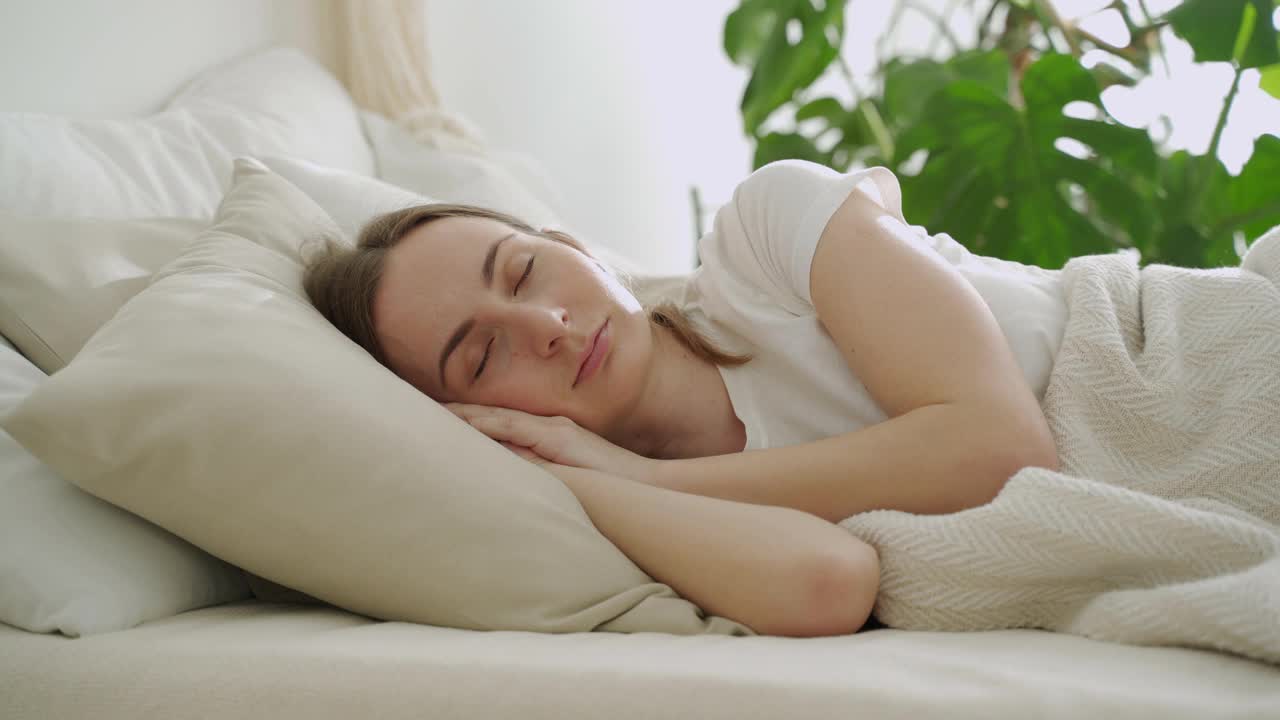 年轻女子睡在白色的枕头上。女人安静地睡在床上视频素材