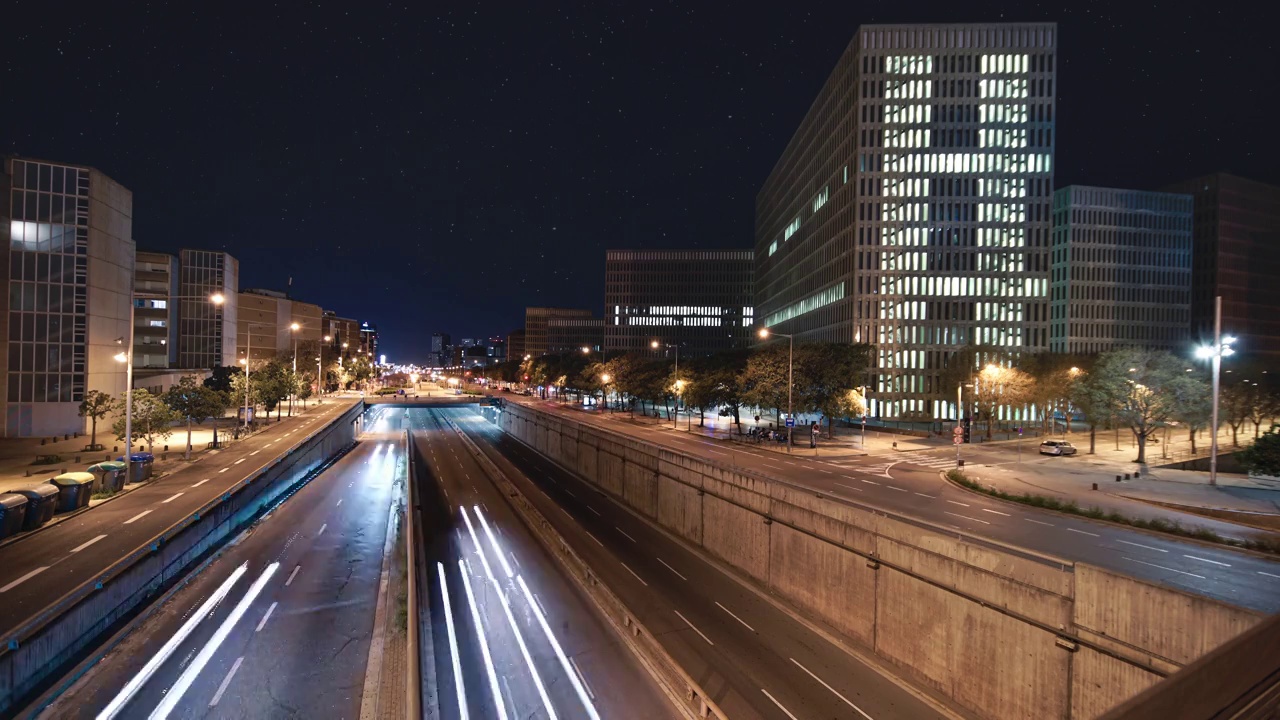 夜晚时光流逝的城市高速公路与快速移动的汽车旅行的现代商业区。在一个繁星满天的美丽夜晚，城市交通的轻轨视频素材