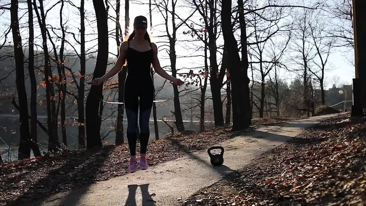 年轻女子跳绳。跳绳女运动员在户外的春天公园里用跳绳运动的女运动员视频素材