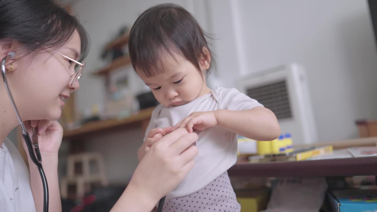 可爱的亚洲小女儿和妈妈玩着医院游戏，拿着听诊器听着心律音视频素材