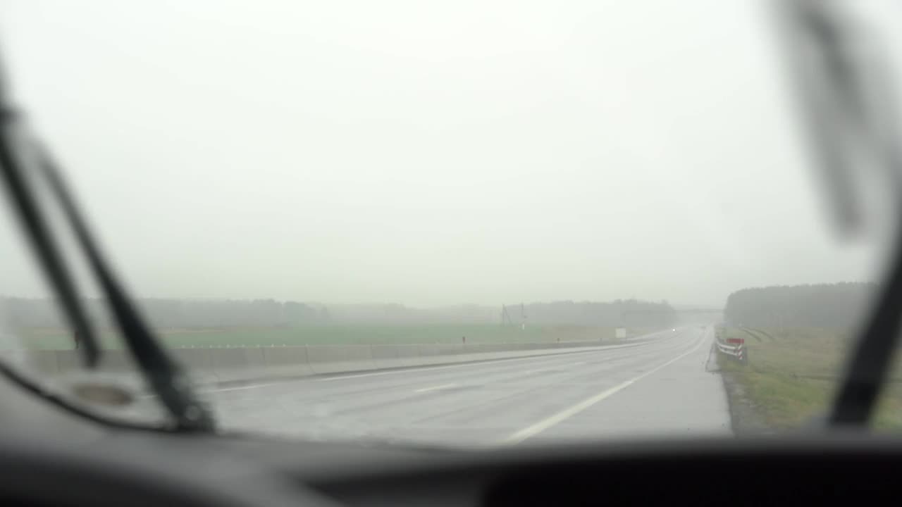 汽车行驶在潮湿的道路之间的视野与雨刷视频素材