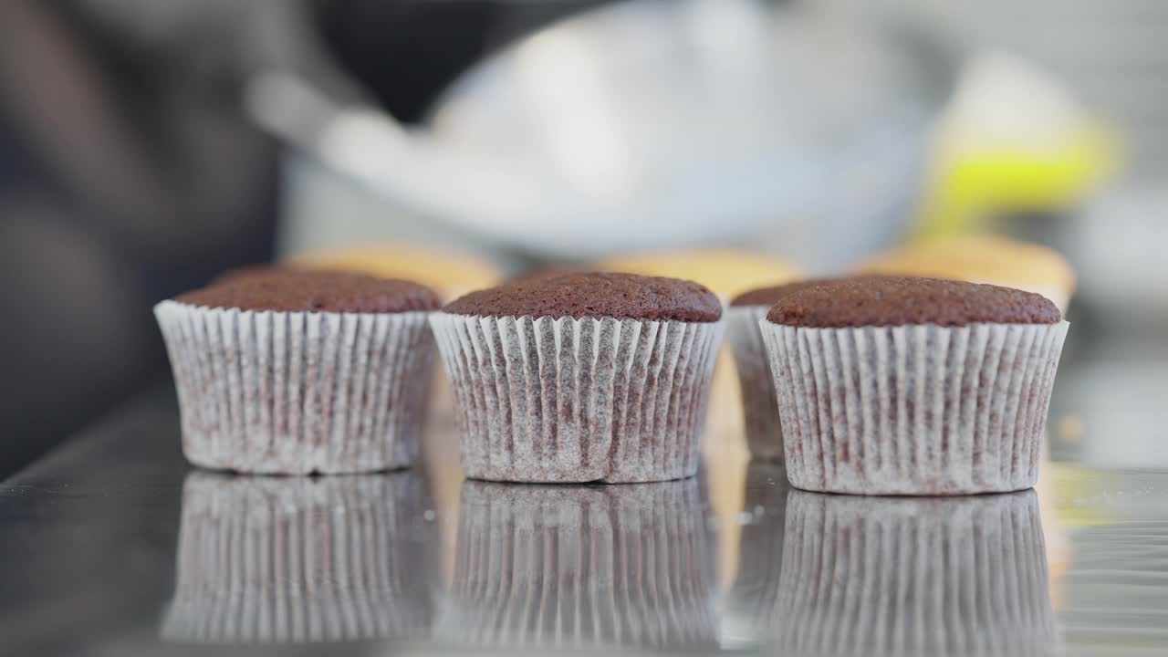 三个棕色松饼的特写在厨房桌子上与模糊的厨师混合浇头在背景。室内美味可口的甜点糖果。糖果店里做的糕点。视频素材