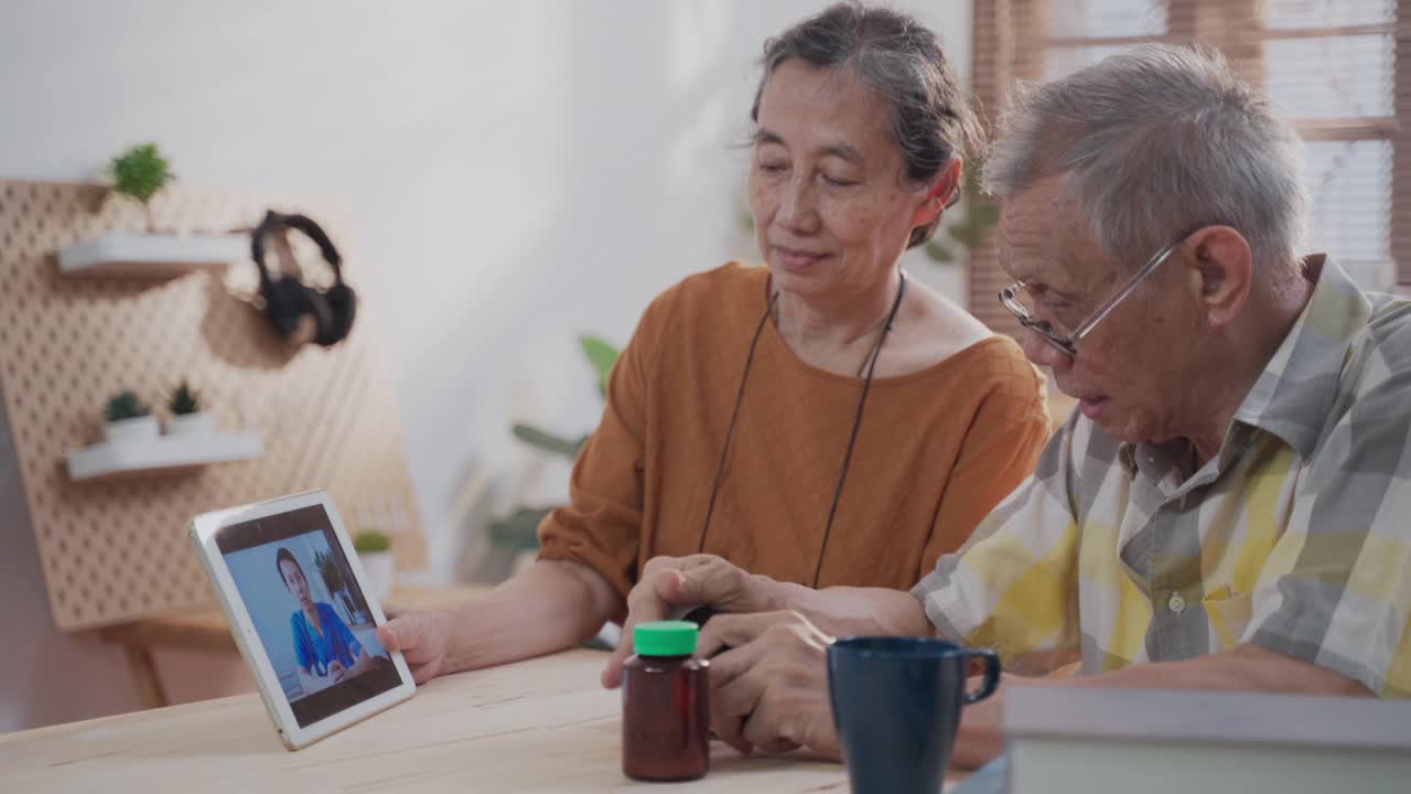 活跃的亚洲老年夫妇在家里用平板电脑与男性医护人员视频通话视频素材