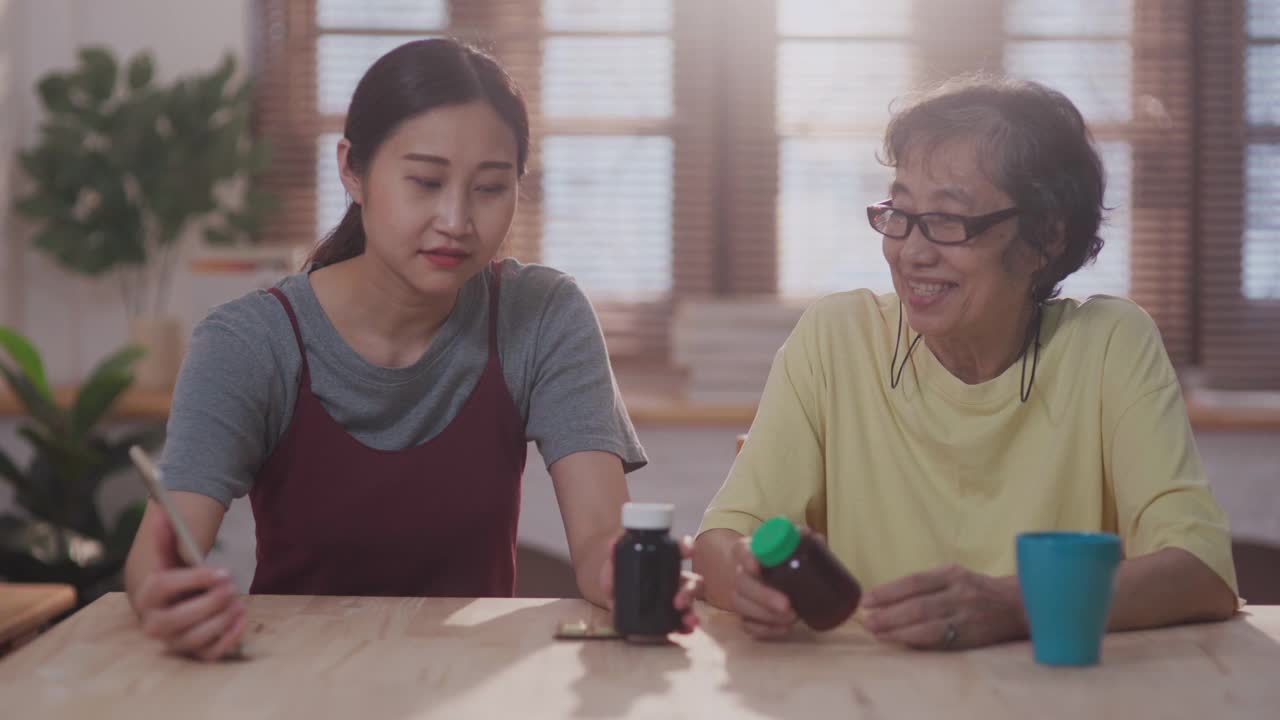 亚洲家庭在客厅，而女儿帮助她的母亲视频电话与男医生在家远程医疗视频素材