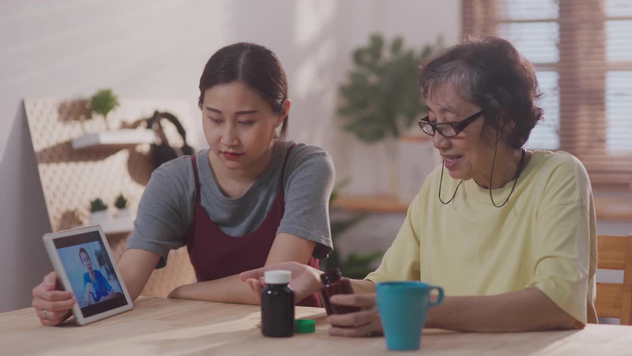 年轻的亚洲女性帮助资深女性缩放视频电话与男性保健工作者在公寓远程保健视频素材