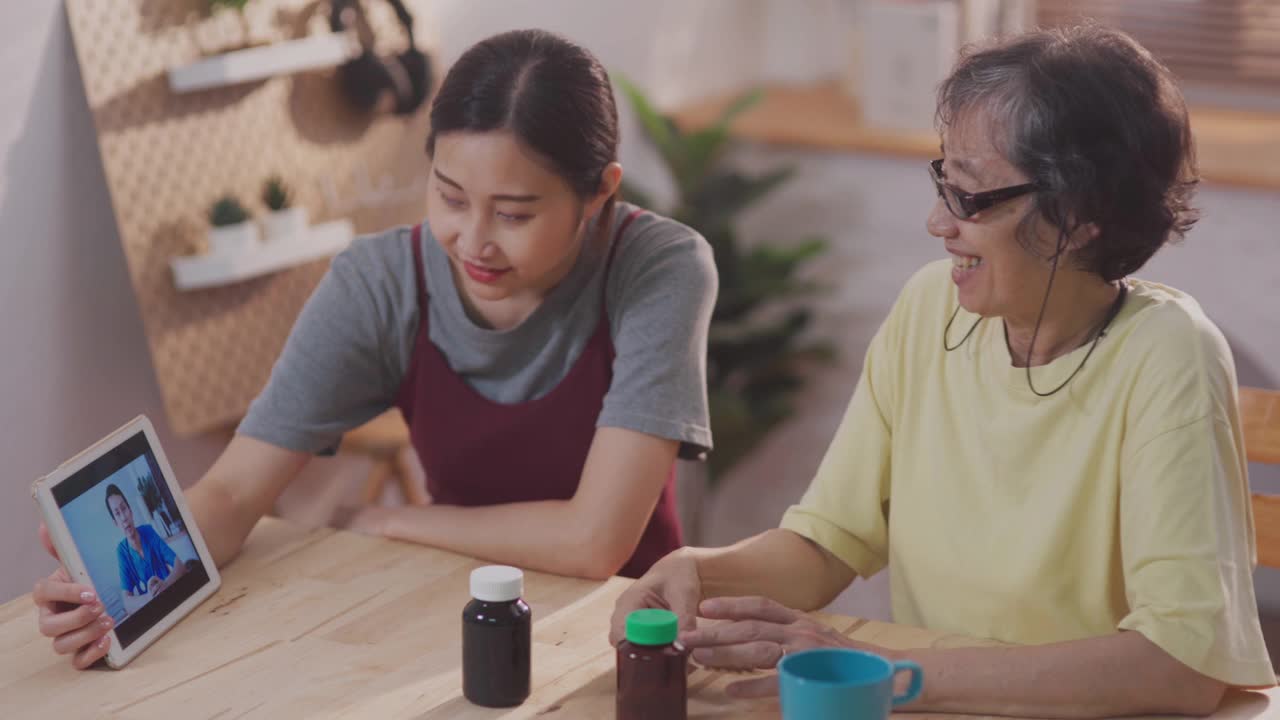 年轻的亚洲女性帮助资深女性缩放视频电话与男性保健工作者在公寓远程保健视频素材