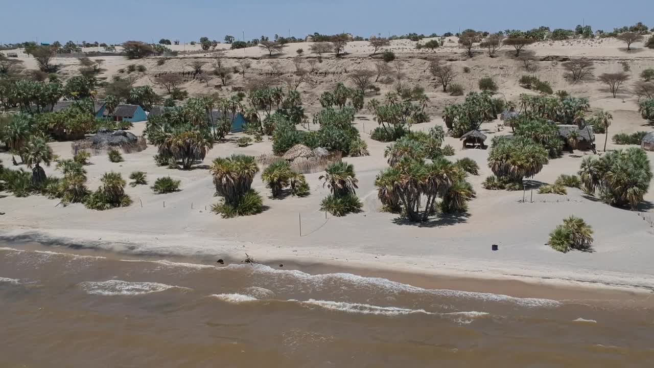 图尔卡纳湖岸，图尔卡纳人的传统小屋，海浪拍打湖岸，摄像机向湖岸移动视频素材