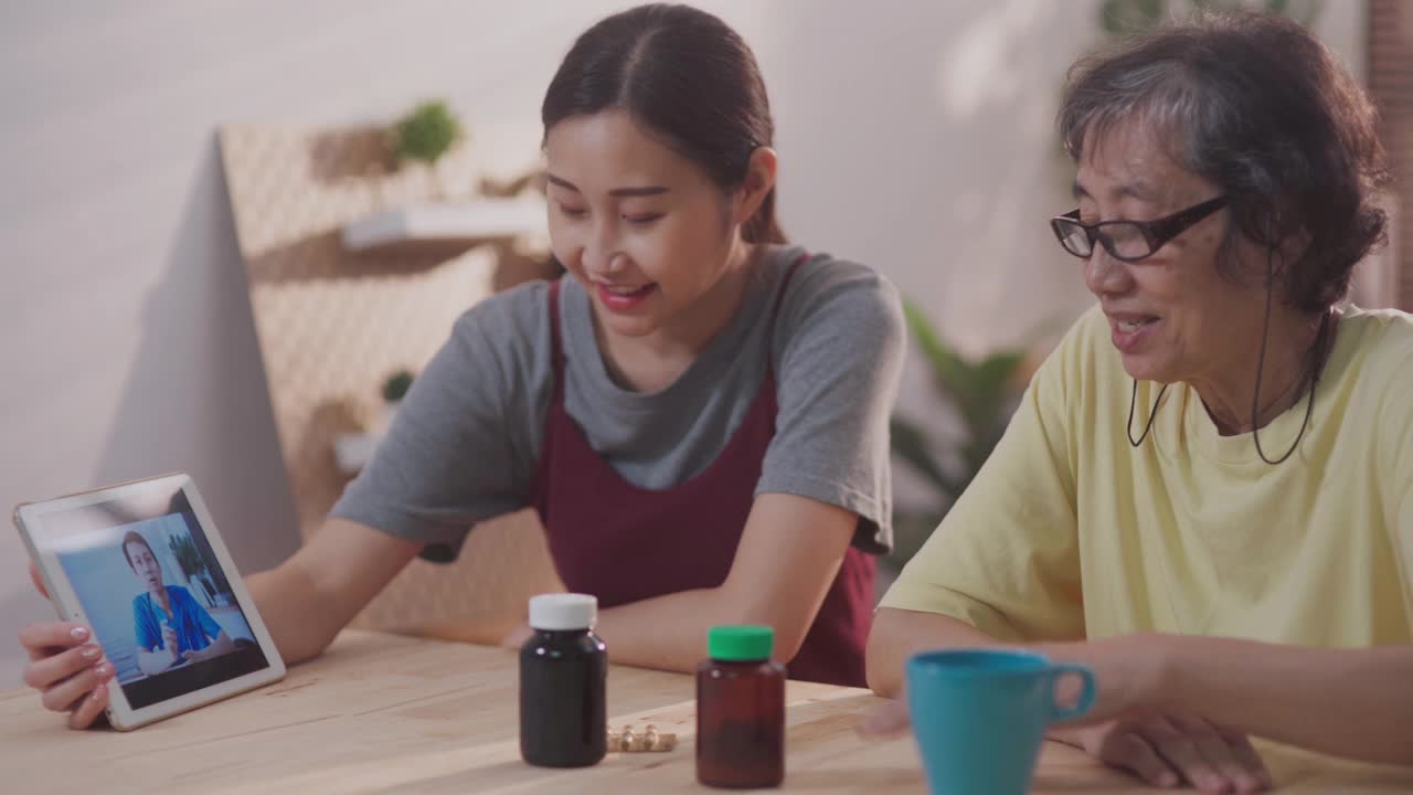 亚洲家庭在客厅，而女儿帮助她的母亲视频电话与男医生在家远程医疗视频素材