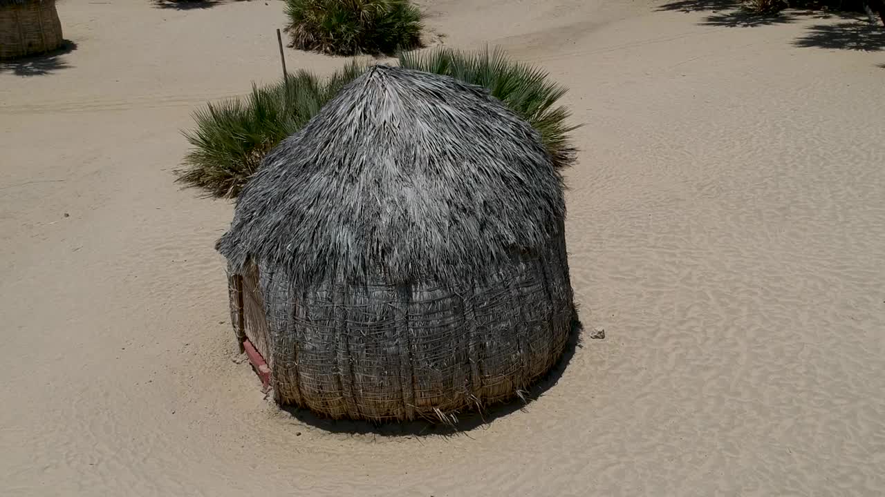 图尔卡纳人用棕榈树叶制作的圆形传统小屋在沙地景观相机上远离小屋Aerial视频素材