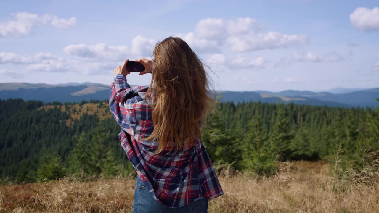 女性徒步旅行者在夏季登山时用智能手机拍照视频素材