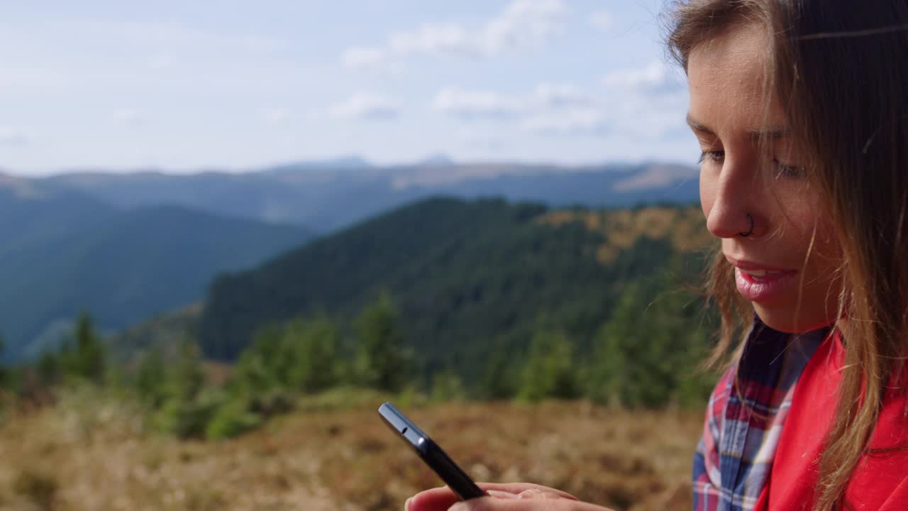 女人在智能手机上滚动触摸屏。女性徒步旅行者在手机上打字视频素材