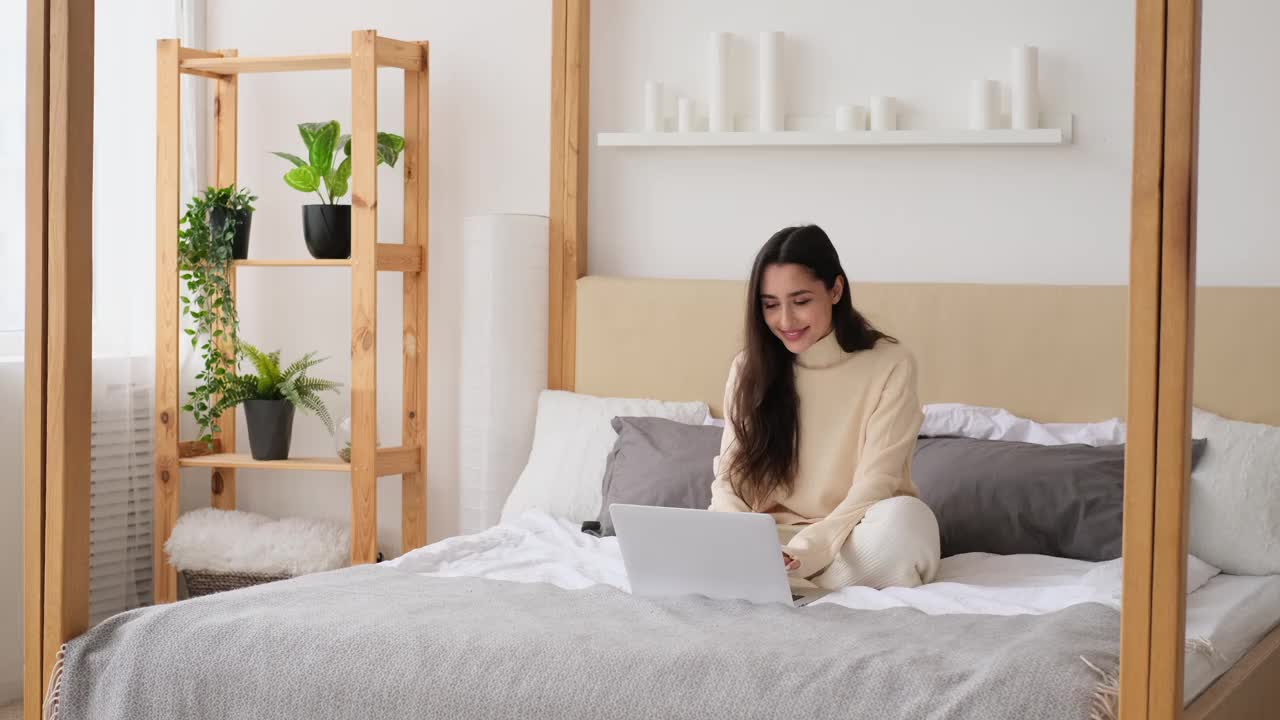 女人笑着在床上用笔记本电脑视频素材