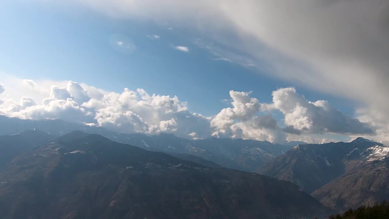 从印度喜马偕尔邦马纳里附近的Bijli Mahadev寺庙看，被雪覆盖的Kullu山谷山峰上，蓬松的白云缓缓飘过视频素材