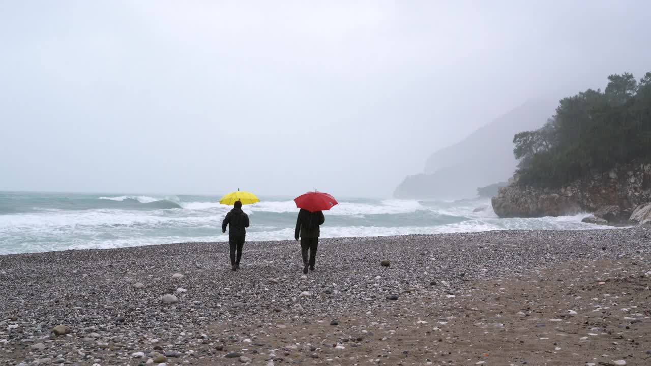 两个男性朋友在一个雨天的海滩上散步视频素材