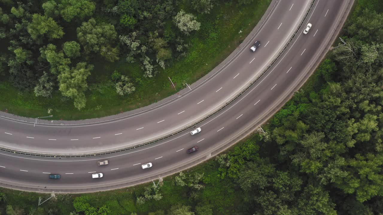 在一段弯曲的道路上的交通在一个延长的俯视图无人机拍摄视频素材