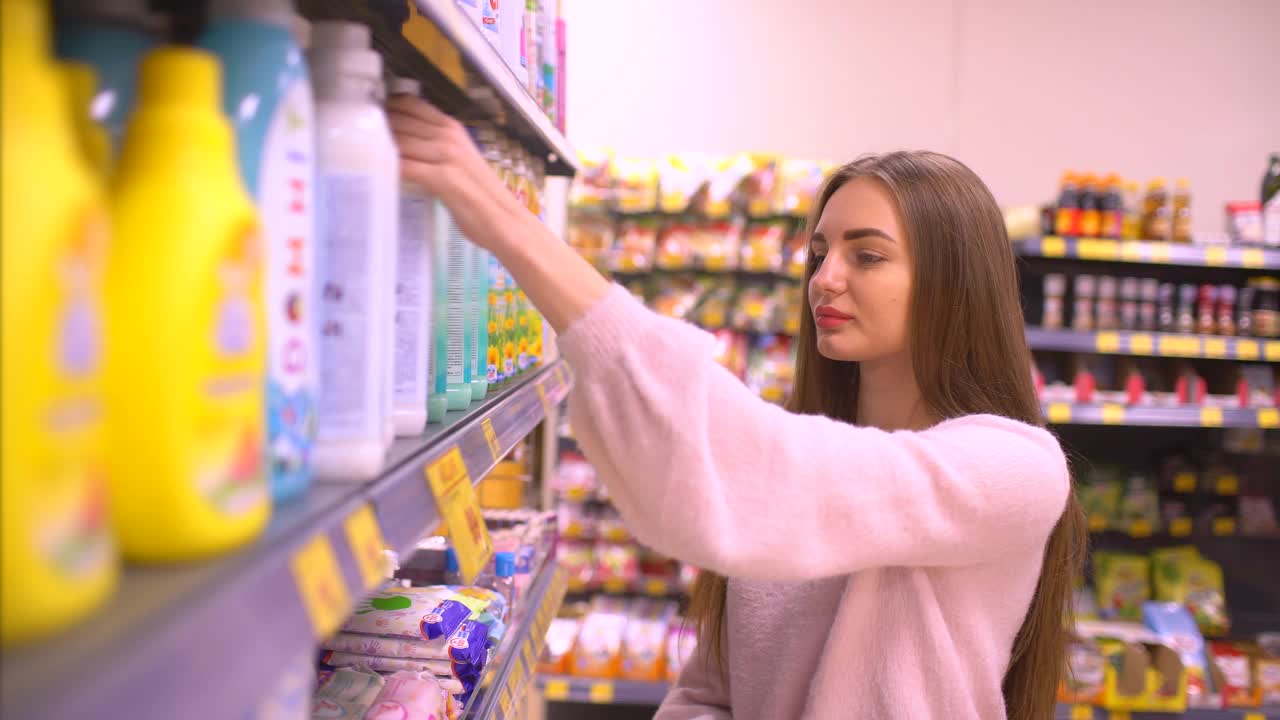 女人在商店里挑选日用化学品。女人在超级市场挑选柔软剂视频素材