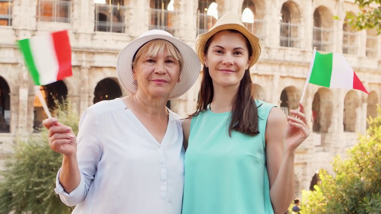 一位高级妇女和她的女儿在罗马竞技场附近挥舞意大利国旗享受假期的肖像视频素材